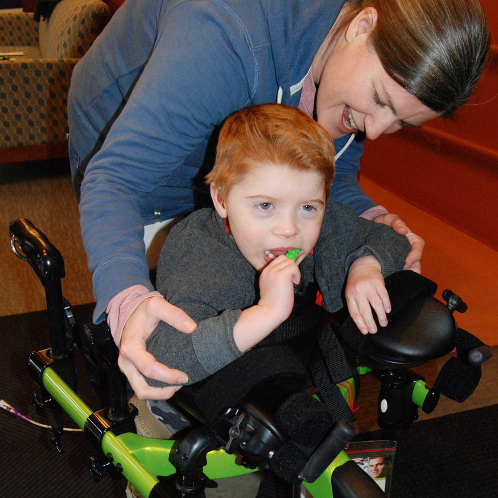 smiling teacher supporting boy in a walker
